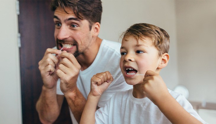 Vater und Sohn benutzen Zahnseide