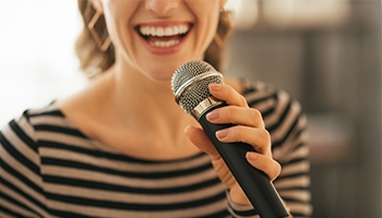 Eine Frau in einem gestreiften Oberteil singt in ein Mikrofon