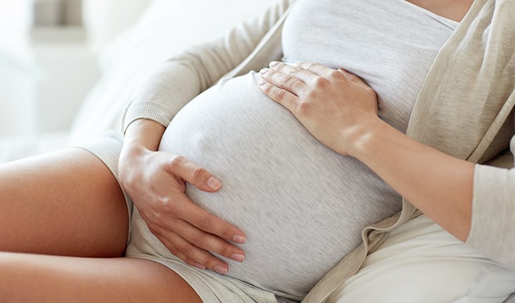 Eine schwangere Frau haelt ihre Haende an ihren Bauch