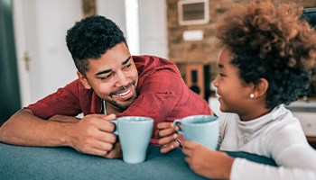 Vater und Tochter sitzen an einem Tisch und trinken Tee