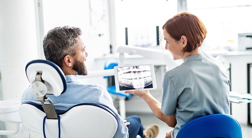 In einer Zahnarztpraxis führen ein Patient und eine Aerztinn ein Gespraech