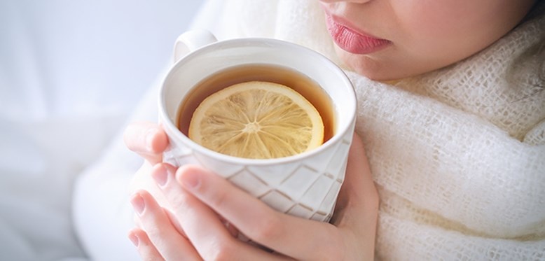 Eine Frau trinkt Tee aus einer weißen Tasse