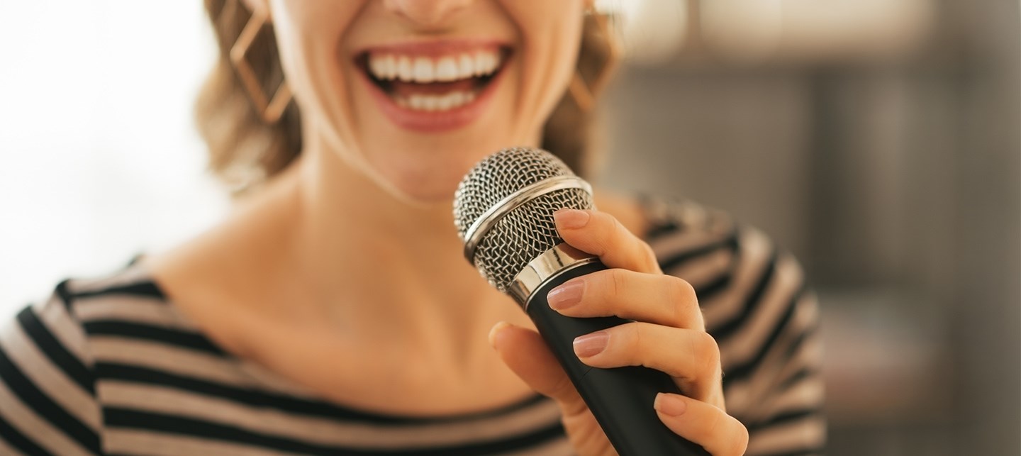 Eine Frau in einem gestreiften Oberteil singt in ein Mikrofon
