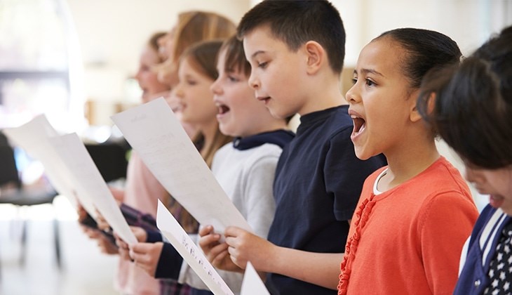 Viele Kinder stehen in einer Reihe und singen im Chor