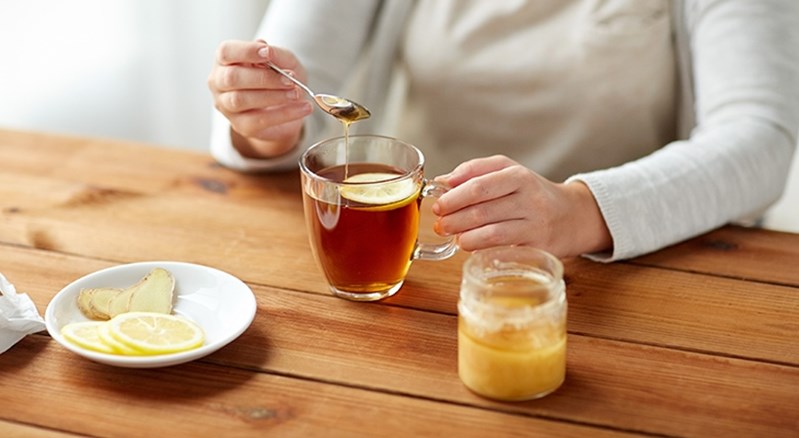 Eine Person gibt Honig ihrem Tee bei