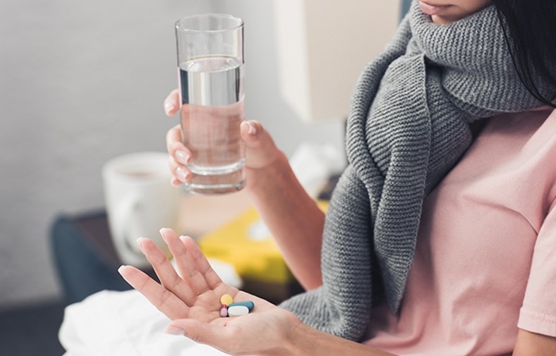 Eine Frau nimmt Medikamente mit einem Glas Wasser zu sich